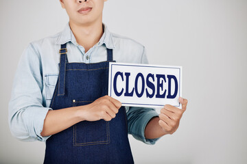 Cropped image of sad young coffeeshop owner showing closed sign