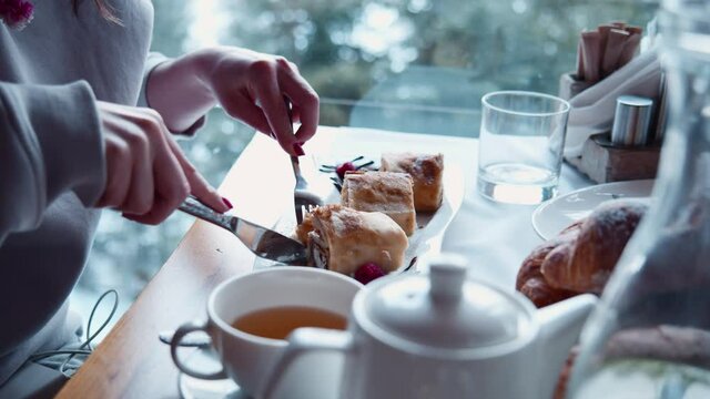 Young woman slicing and eating delicious baked pancakes in the cafe. Morning breakfast in continental restaurant. All inclusive resort hotel. Luxury lifestyle.