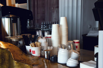 Close-up view of various disposable wooden sticks, wooden spoon, tooth sticks, cup covers, Take away boxes, napkins and sugar bags on wooden counter in cafe for self-service and take away drinks