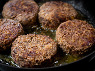 Beef burgers fried in frying pan.