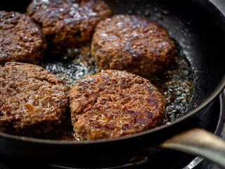 Beef burgers fried in frying pan.