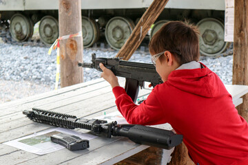 young boy with a machine gun in the outdoor shooting gallery