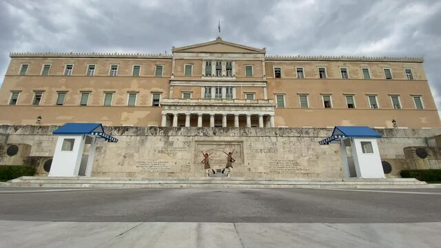 Greek presidential guard Evzones in traditional outfit performing the changing guard procedure in front of the unknown soldier monument in the center of Athens with dark clouds moving fast above Vouli