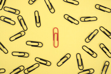 Business leadership concept, think creatively and stand out from the crowd. Be different concept as a group of paper clips on canvas with one person in the opposite direction.