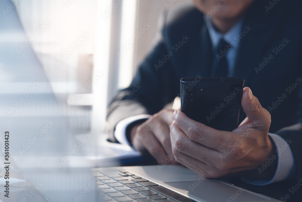 Poster close up of businessman using mobile phone working on laptop computer in office