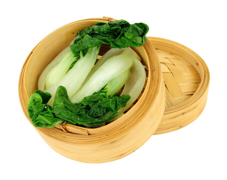 Freshly steamed pak choi Chinese cabbages in a bamboo steamer isolated on a white background