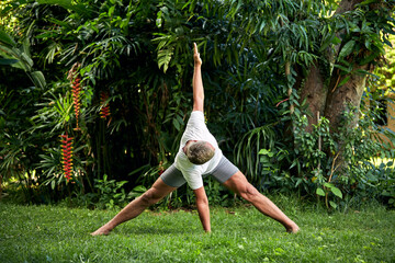 Man practice yoga in the tropical garden