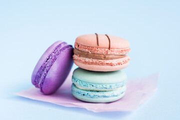 Close up view of three French macaroons on a blue background. Sweet and colorful French macaroons. Dessert. Homemade sweets. Café dessert. Selective focus