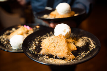 Crispy pastry dessert, melted cheese inside and sprinkled with crushed pistachios. Dessert served with a scoop of white ice cream.