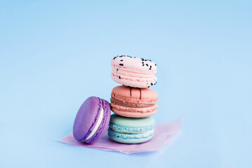 Close up view of stack of French macaroons on a blue background. Sweet and colorful French macaroons. Dessert. Homemade sweets. Café dessert. Selective focus