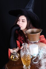 Vertical closeup shot of Caucasian female with red ombre hair in a black witch costume with potions