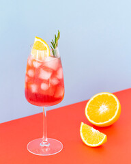 Aperol cocktail on a colors background. Cold drink with ice cubes. Glass of aperol spritz with...
