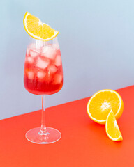 Aperol cocktail on a colors background. Cold drink with ice cubes. Glass of aperol spritz with...