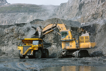 Excavator loads ore into a mining dump truck.