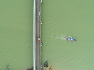 Aerial shot of a fishing boat passing under a bridge