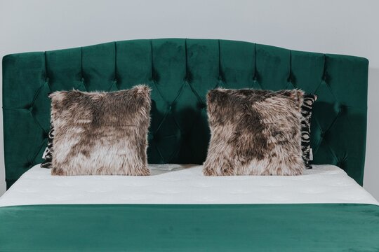 Queen-size Bed With Deep Green Velvet Headboard And Fluffy Cushions