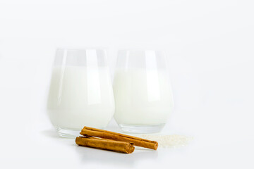 Two glass of vegatarian fermented rice drink Amazake. Non-alcoholic drink, cinnamon sticks and cereal rice on white background