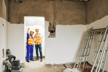 Contractor talking with walkie-talkie with builder showing his room with freshly plastered brick walls