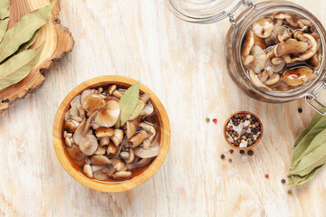 Homemade pickled honey agarics in wooden bowi and  open glass jar, spices, spoon, napkin,  on  wooden table. Marinated mushrooms are valuable source of protein. Fermented healthy food.