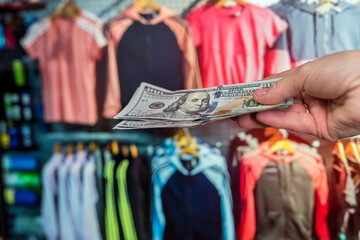 man pays in dollars for buying clothes in a store