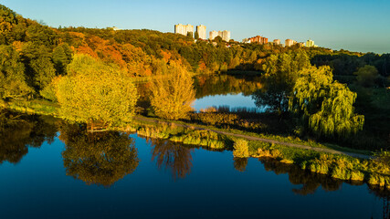 Golden autumn background, aerial drone view of forest with yellow trees and beautiful lake landscape from above, Kiev, Goloseevo forest, Ukraine
