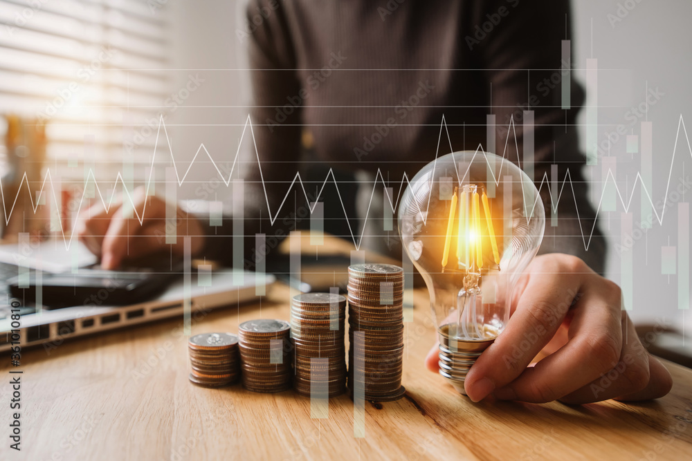 Poster business hand holding lightbulb with using laptop computer and money stack in office. idea saving en