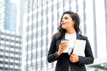 Portrait of beautiful young confident Hispanic businesswoman taking a coffee break holding tablet in urban city background