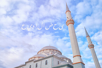 Eid Mubarak description on arabic script and minarets of a mosque opposite cloudy blue sky