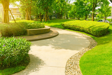 Landscape of green grass lawn and trees, seating on gray curve pattern walkway sand washed paving