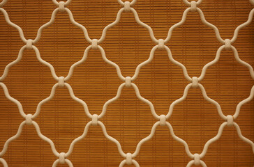 Diamond pattern of white curved wrought iron steel on the lattice window, orange bamboo curtain...