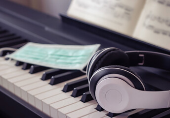 Obraz na płótnie Canvas Music and new normal concept , Top view of hygienic surgical mask on piano keyboard with headphones