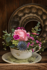 Obraz na płótnie Canvas Old coffee cup with flower arrangement on a table