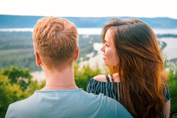 A young couple in love blond men and brunette women watch the sunset on a panorama of the mountains...