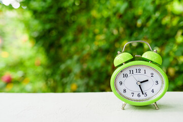 green Alarm Clock in Vintage Style with Nature and Wood Background. copy space