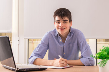 teenager studying with laptop at home or at school