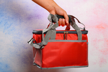 hand holding a red lunch pack carrier or insulation bag