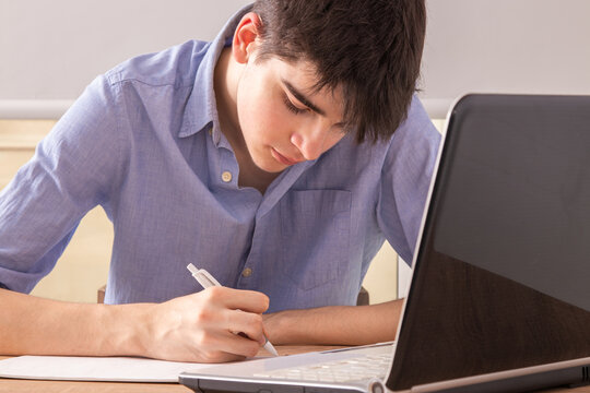 teenager studying with laptop at home or at school