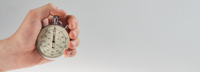 hand holding a stopwatch on a gray background