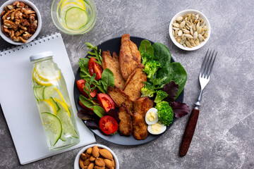 A plate of healthy food with baked chicken, herbs, vegetables, nuts and a detox drink. KETO diet concept.