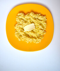 Millet porridge with butter in a yellow plate on a white background