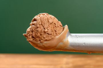 side view spoon taking out an ice cream ball from box of chocolate flavor ice cream