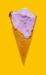 angle view sweet potato flavor ice cream cone with some bites on yellow background