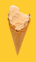 angle view milk tea flavor ice cream cone with some bites on a yellow background