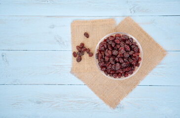 Dried cranberries in glass bowl on wooden blue plank.Top view.
