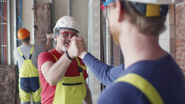 Builders colleagues shaking hands greeting on construction site
