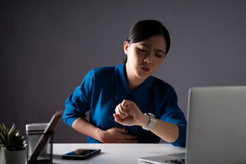 Asian woman in blue shirt was sick with stomach ache sitting at office. isolated on white...