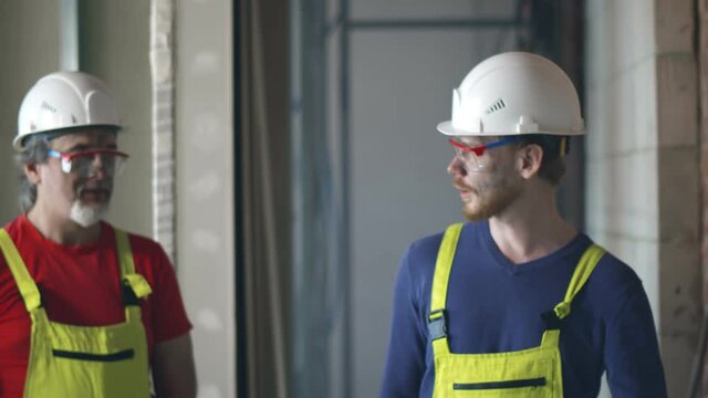 Happy Construction Workers Smiling and Talking In New Building