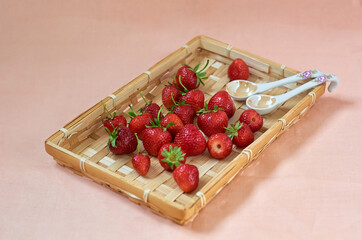 ripe red strawberries in a wicker brown basket on a scarlet background