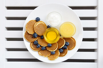 Pancake cereal with honey, yogurt, milk and blueberry on white