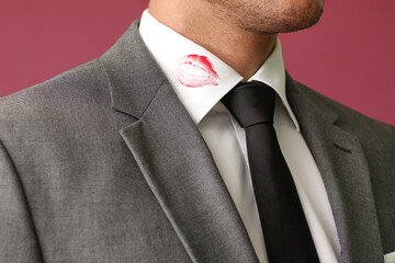 Young businessman with lips print on shirt collar against color background, closeup